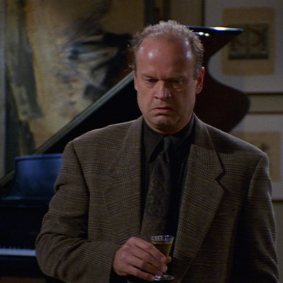 Frasier is standing with a Sherry in his hand and a resignedly expression on his face.